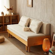 a living room with a white couch and bookshelf in the corner next to a window