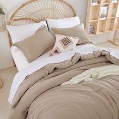 a bed with pillows and blankets on top of it next to a book shelf filled with books