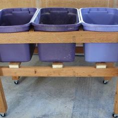 four purple plastic containers are sitting on a wooden cart