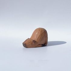 a wooden sculpture of a bear's head on a white surface with a shadow