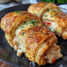 three pastries on a black plate with parsley sprinkled around the edges