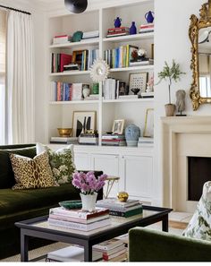 a living room filled with furniture and a fire place under a mirror on top of a book shelf