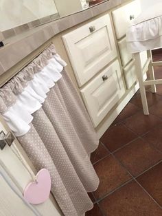 a white sink sitting next to a counter top under a bathroom mirror with a pink heart hanging on it's side