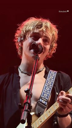 a young man singing into a microphone while holding an electric guitar in front of him