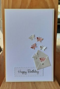 a birthday card with butterflies flying out of an envelope on top of a wooden table