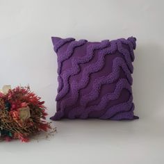 a purple decorative pillow sitting next to a dried flower