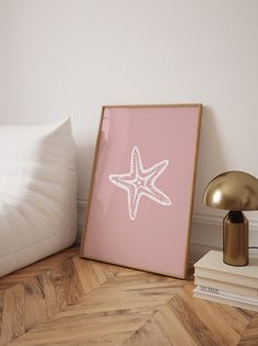 a starfish print on a pink background next to a lamp and books in a bedroom