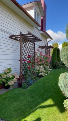 a garden with flowers and plants next to a house