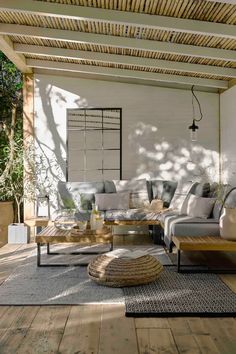 an outdoor living room with wood floors and white walls