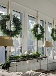 a window with wreaths on the windowsill in front of it and two lamps next to them