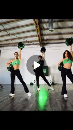 three women in green cheerleader outfits are dancing on the dance floor with their hands up