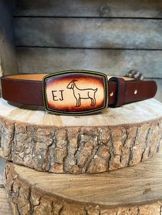 a belt with a horse on it sitting on top of a piece of wood next to a log