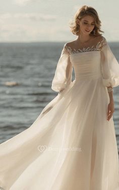 a woman in a white dress standing on the beach