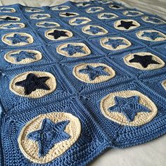 a blue crocheted blanket with black and white stars on it, sitting on top of a bed