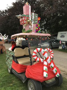 a golf cart decorated for christmas with candy canes and gifts on top, in the grass