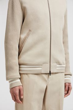 Crafted from cotton, this cardigan is enhanced with a down-filled nylon back. The lightweight style comes in a bomber shape, complete with a striped knit trim. Luxury Cotton Sweater With Ribbed Cuffs, Beige Wool Cardigan With Ribbed Cuffs, Cream Cotton Cardigan With Ribbed Cuffs, Cream Wool Outerwear With Ribbed Cuffs, Wool Outerwear With Ribbed Cuffs In Cream, Beige Cotton Cardigan With Ribbed Cuffs, Beige Sporty Outerwear With Ribbed Cuffs, Sporty Beige Outerwear With Ribbed Cuffs, Casual Wool Sweater With Striped Cuffs