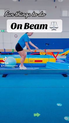 a woman in blue shirt and black shorts standing on top of a trampoline