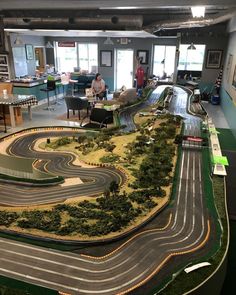 a model race track in the middle of a room with people sitting at tables around it