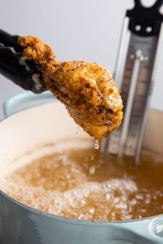 a chicken wing is being cooked in a saucepan with a thermometer on it