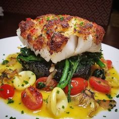 a white plate topped with fish and vegetables