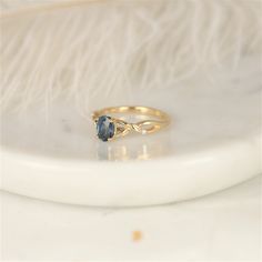 a gold ring with a blue topazte sits on a white marble tablecloth