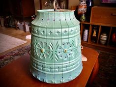 a green vase sitting on top of a wooden table