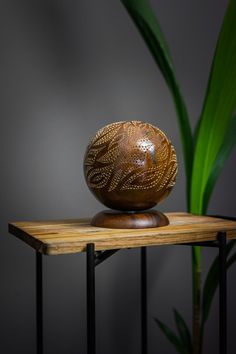 a wooden bowl sitting on top of a table next to a green leafy plant