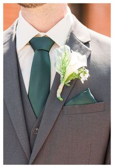 a man wearing a suit and tie with a boutonniere on his lapel