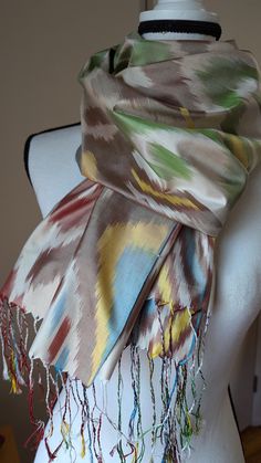 Made from 100% handwoven silk . Beautiful Ikat pattern with fringe. This scarf would make a lovely gift. Ship from the U.S.! This  silk scarf comes from Margilan region from Uzbekistan.  Each scarf is hand-woven by artisans and craftspeople. Each scarf is unique with different variations in technique and weave. The slight variations and inconsistencies add to its uniqueness.  Colors were produced using dyes from natural ingredients such as, walnuts, pomegranates, onions, and the indigo plant. No chemicals were used in the production of this silk. Colors are permanent and will not bleed onto clothing. Handwash only. Wash it in a cold water with a little bit shampoo or special silk detergent. Luxury Art Silk Shawl With Zari Weaving, Ikat Scarf, Silk Colors, Indigo Plant, Silk Ikat, Ikat Pattern, Shawls And Wraps, Onions, Silk Scarf