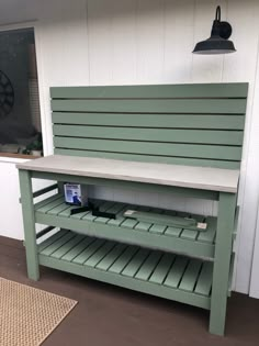 a green bench sitting on top of a hard wood floor next to a white wall