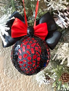 a mickey mouse ornament hanging from a christmas tree with red and black bows