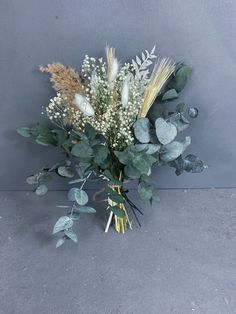 a bouquet of flowers sitting on top of a cement floor next to a gray wall