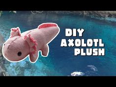 an axoloi plush toy hanging from the side of a wall next to water