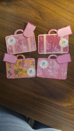 four pieces of pink luggage sitting on top of a wooden table