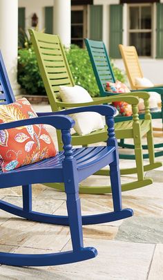 three colorful rocking chairs sitting on a patio