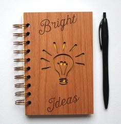 a wooden notebook with the words bright ideas written on it next to a black pen