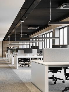 an empty office with desks and chairs in the middle of it, along with hanging lights