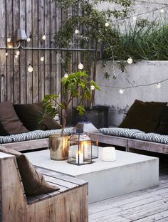 an outdoor living area with couches, tables and lights