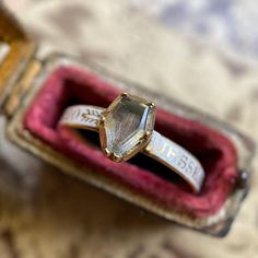 An untouched & pristine Georgian era mourning ring, rare in the unmarred white enamel that covers the rounded, convex shank; as well as the flawless coffin shaped crystal bezel that studs the front. Under the coffin, a stretch of tightly straight brown hair--still laying flat, prim and very orderly to this day.  The white color of the shank indicates the status of the deceased as unmarried or very young and alludes to pureness and innocence. The enamel, intact, solid and very finely done serves as the background for capital golden letters spelling out the deceased's details. There are several different flourishes in between the words of dedication on the shank, which is unusual and unique as more often than not in these examples there are typically maybe one or repeated motifs.  The uprigh Georgian Era, Rock Crystal, White Enamel, Art Jewelry, Stackable Rings, Unique Rings, 18th Century, Brown Hair, Jewelry Art