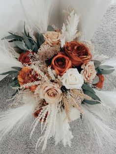 an arrangement of flowers and feathers is displayed on the floor in front of a wall