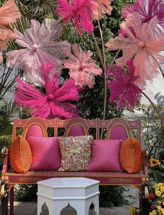 a bench with pink and orange pillows sitting on it's side in front of flowers