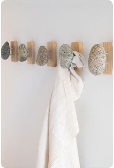 a towel hanging on the wall next to three rocks and two wooden pegs with one rock embedded in it