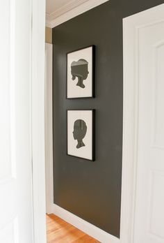 two black and white pictures hang on the wall next to each other in a hallway