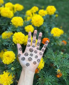 a person's hand painted with black and white flowers in front of yellow flowers