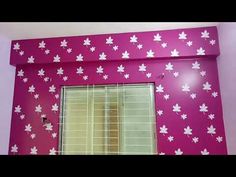 a pink wall with white flowers painted on it and a window in the middle,