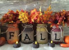 three jars with fall decorations in them sitting on a table