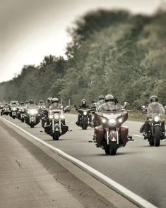 a group of motorcyclists are riding down the road in front of each other