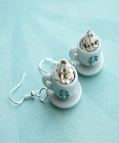 two white cups filled with whipped cream sitting on top of each other next to silver earwires