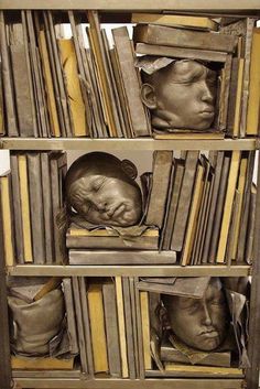 several bookshelves with sculptures of people sleeping on them, all made out of books