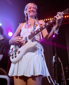 a woman playing an electric guitar on stage